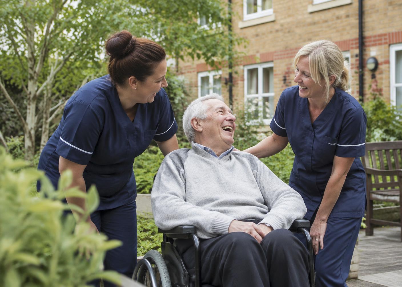 Two care staff laughing with an elderly resident in a care home garden